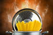 Hot spaghetti inside a pot on the brown background