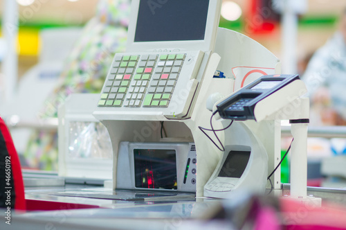 Photo: Cash-desk with terminal in supermarket. Customers on background Cash-desk with terminal in supermarket. Customers on background