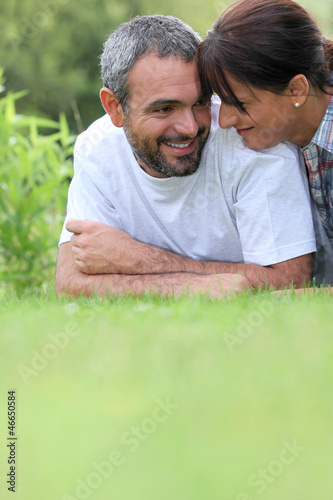 Photo: Couple laying in field Couple laying in field