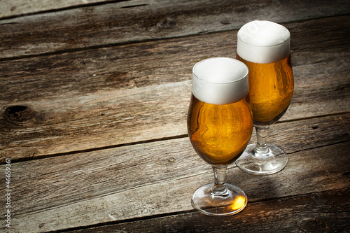 Photo: Two glass beer on wood background with copyspace Two glass beer on wood background with copyspace