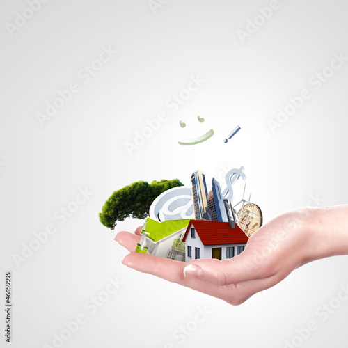 Photo: Human hand against blue sky background and house Human hand against blue sky background and house