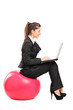Foto: Busy woman sitting on a pilates ball and working on a notebook c Busy woman sitting on a pilates ball and working on a notebook c