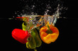 Red, green and yellow bellpepper falling into the water