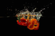 Slices of red and yellow peppers falling into the water
