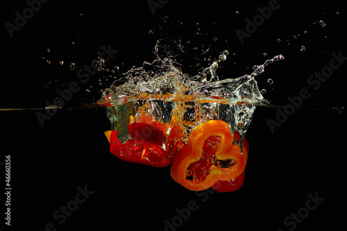 Photo: Slices of red and yellow peppers falling into the water Slices of red and yellow peppers falling into the water