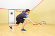 Squash player hiting a ball in a squash court