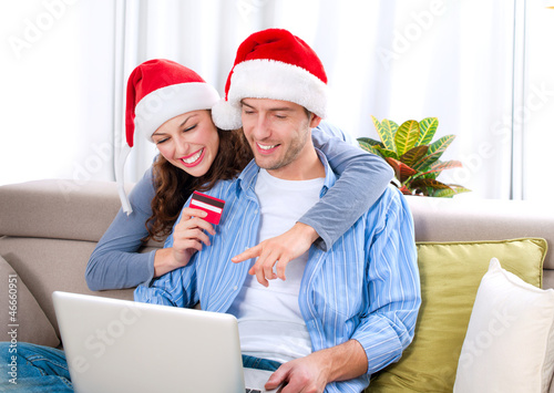 Photo: Christmas Online Shopping. Couple Using Credit Card to E-Shop Christmas Online Shopping. Couple Using Credit Card to E-Shop