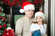Girl and father in Santa hats write letter to Santa