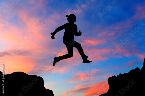 Photo: Silhouette of hiking woman jumping over the mountains at sunset Silhouette of hiking woman jumping over the mountains at sunset