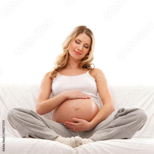 Photo: A young blond pregnant woman sitting in indoor clothes A young blond pregnant woman sitting in indoor clothes