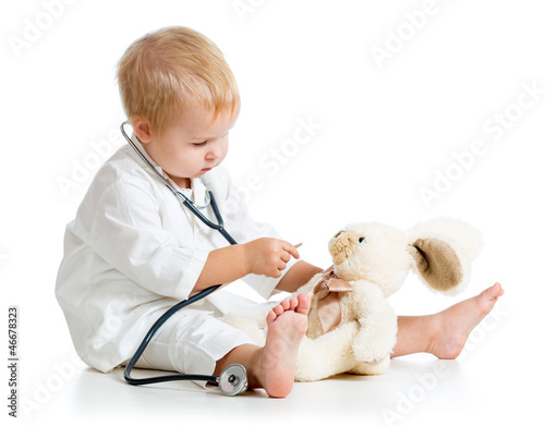 Photo: Adorable child dressed as doctor playing with toy over white Adorable child dressed as doctor playing with toy over white