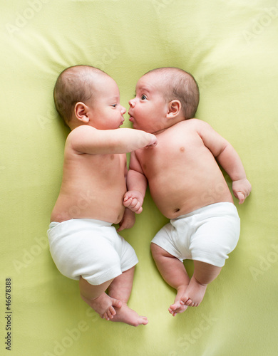 Photo: funny twins brothers babies lying on green funny twins brothers babies lying on green
