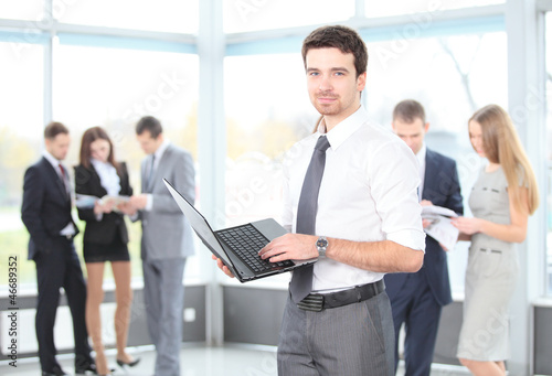 Photo: Smart business man using laptop with colleagues Smart business man using laptop with colleagues