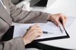 Hand mit Stift und Klemmbrett