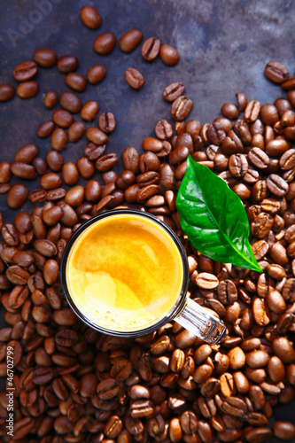 Photo: Cup of rich frothy coffee with coffee beans Cup of rich frothy coffee with coffee beans