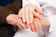 Young doctor holds the elderly woman hands