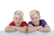 Zwei blonde Zwillinge lachen nebeneinander