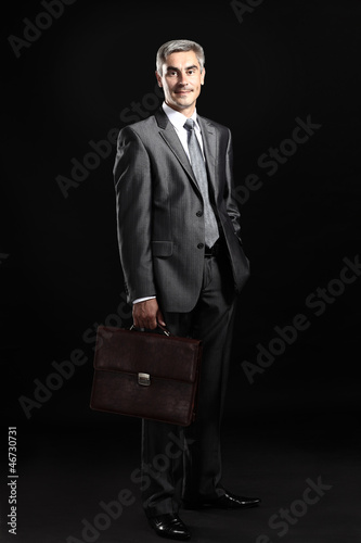 Photo: Closeup of a smiling senior man isolated over black background Closeup of a smiling senior man isolated over black background