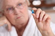 An old woman taking a pill.