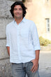 Man casually leaning against stone building