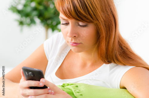 Photo: junge frau schaut traurig auf ihr smartphone junge frau schaut traurig auf ihr smartphone