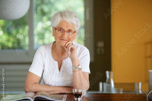 Photo: Grandmother reading magazine in the kitchen Grandmother reading magazine in the kitchen
