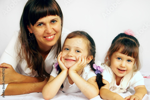 Photo: Happy mother and two daughters are on the floor Happy mother and two daughters are on the floor