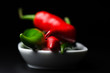 Photo: Cayenne pepper in white plate on dark background close up Cayenne pepper in white plate on dark background close up