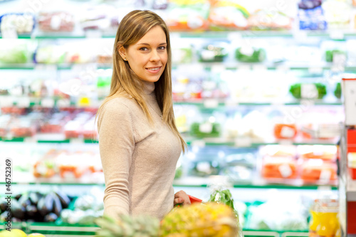 Photo: Smiling woman shopping with trolley in supermarket Smiling woman shopping with trolley in supermarket
