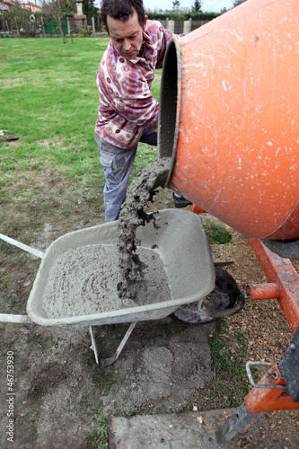 Photo: Man pouring cement into wheelbarrow Man pouring cement into wheelbarrow