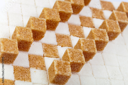 Photo: Cubes of not refined reed sugar lie on pieces of white sugar.. Cubes of not refined reed sugar lie on pieces of white sugar..