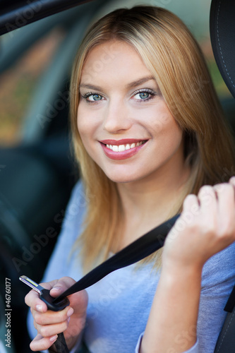 Photo: Woman attaching seat belt in car Woman attaching seat belt in car
