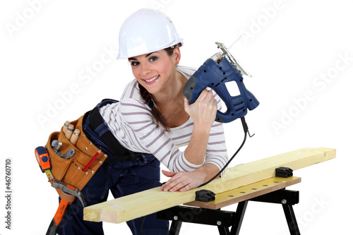 Photo: Young woman using a jigsaw Young woman using a jigsaw