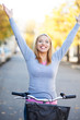 Woman with arms raised while sitting on bike