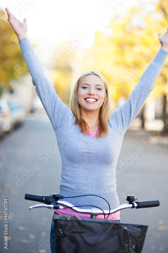 Photo: Woman with arms raised while sitting on bike Woman with arms raised while sitting on bike