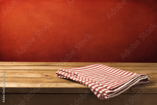 Photo: Background with wooden table, tablecloth and grunge red wall Background with wooden table, tablecloth and grunge red wall