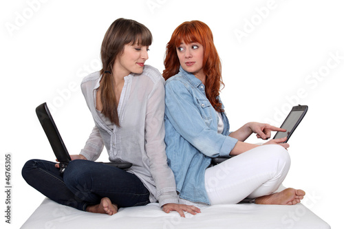 Photo: Two friends back to back over their laptops. Two friends back to back over their laptops.