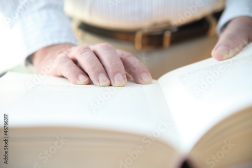 Photo: man with his hands on a large book man with his hands on a large book