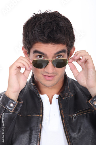 Photo: Young man wearing leather jacket and trendy sunglasses Young man wearing leather jacket and trendy sunglasses
