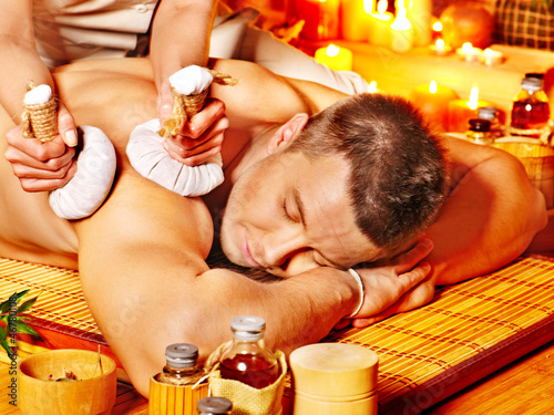 Photo: Man getting herbal ball massage treatments . Man getting herbal ball massage treatments .