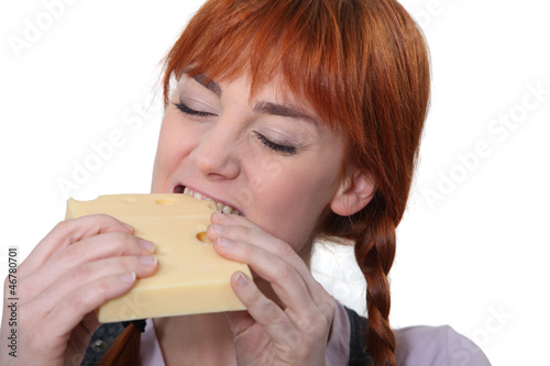 Photo: Woman biting into a piece of cheese Woman biting into a piece of cheese