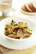 Stewed chanterelles with green onions in a white bowl