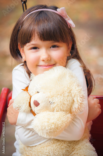 Photo: Small beautiful girl and amusing bear Small beautiful girl and amusing bear
