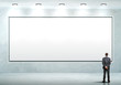 Business person standing near a blank billboard