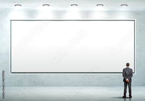 Photo: Business person standing near a blank billboard Business person standing near a blank billboard