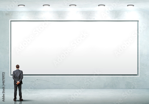 Photo: Business person standing near a blank billboard Business person standing near a blank billboard