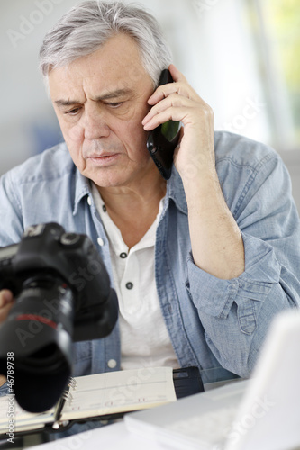Photo: Photographer in office talking on the phone with client Photographer in office talking on the phone with client