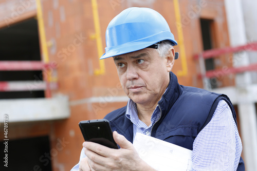 Photo: Entrepreneur on construction site using smartphone Entrepreneur on construction site using smartphone