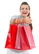 Smiling woman in sweater showing thumbs up with shopping bags
