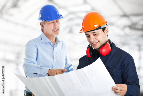 Photo: Couple of engineers reading a blueprint Couple of engineers reading a blueprint